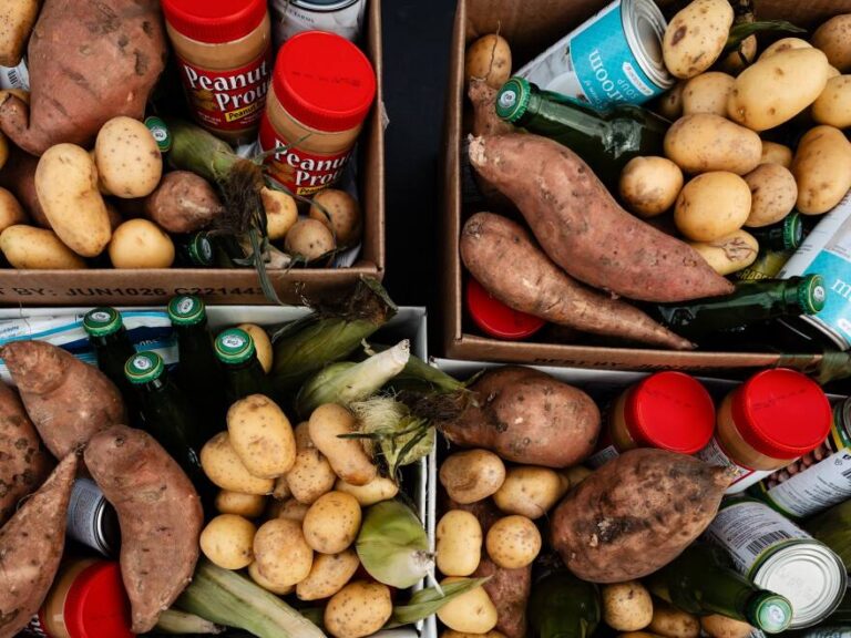 Food pantry boxes filled with potatoes, sweet potatoes, corn, peanut butter and canned goods