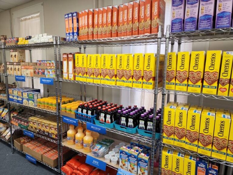 Food pantry shelves stocked with cereal, pasta sauce, peanut butter, jelly and juice