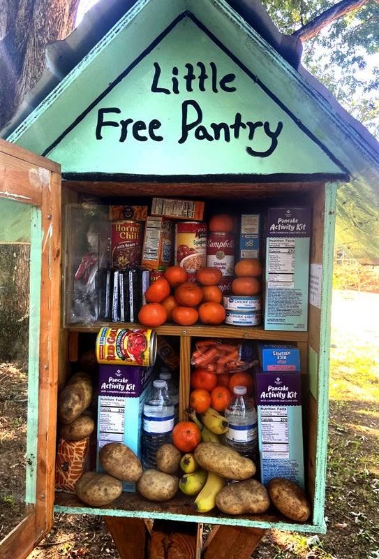 Little free pantry cabinet stocked with canned food, fresh produce and bottled water